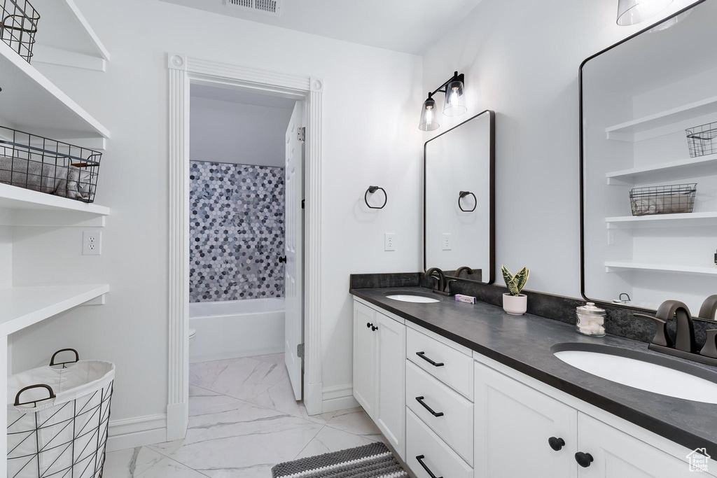 Bathroom featuring marble finish flooring, double vanity, baseboards, and  shower combination