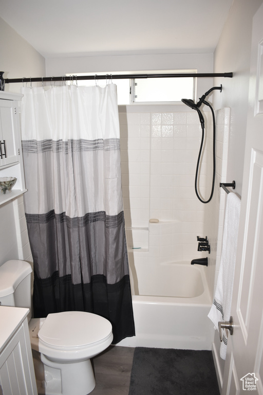 Full bath featuring toilet, vanity, shower / bath combo, and wood finished floors