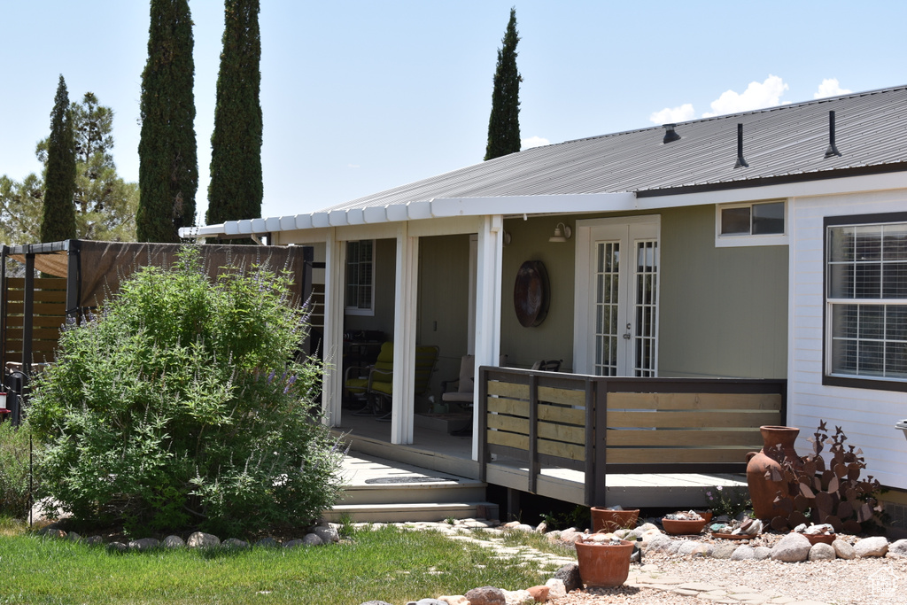 View of front of house with french doors, metal roof, and a wooden deck