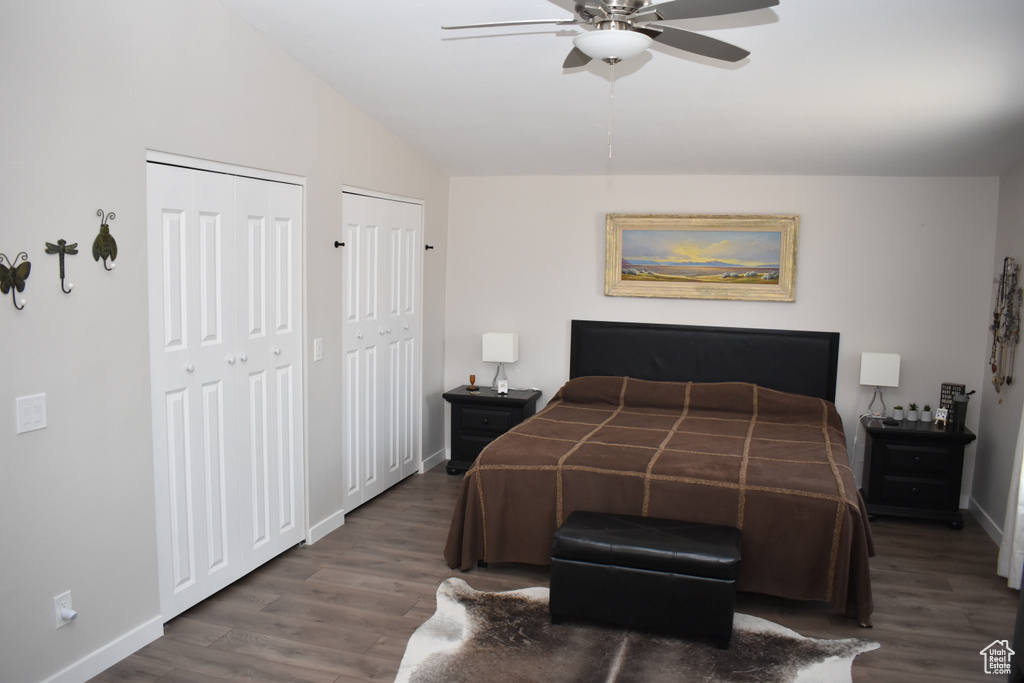 Bedroom featuring multiple closets, wood finished floors, baseboards, vaulted ceiling, and ceiling fan