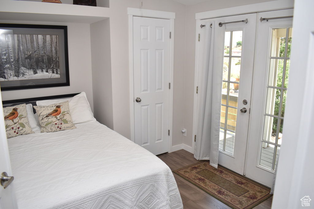 Bedroom with wood finished floors, access to exterior, and baseboards