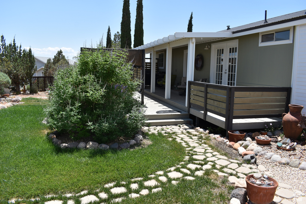 View of grassy yard with french doors and a deck