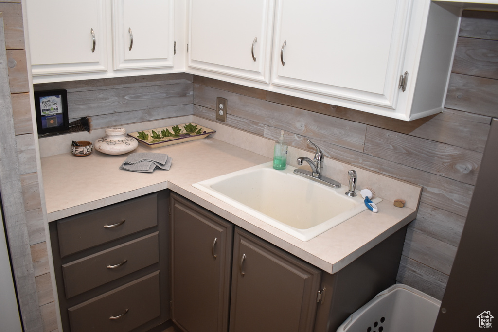 Kitchen with light countertops, a sink, white cabinets, tasteful backsplash, and gray cabinets