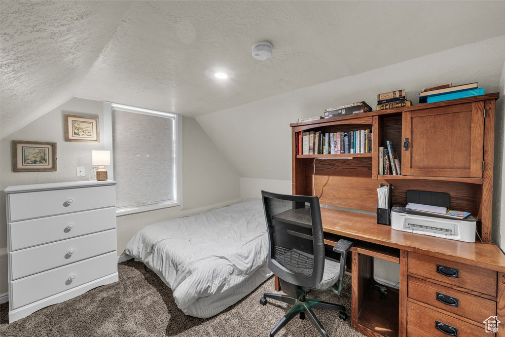 Bedroom featuring a textured ceiling, lofted ceiling, carpet floors, and a desk