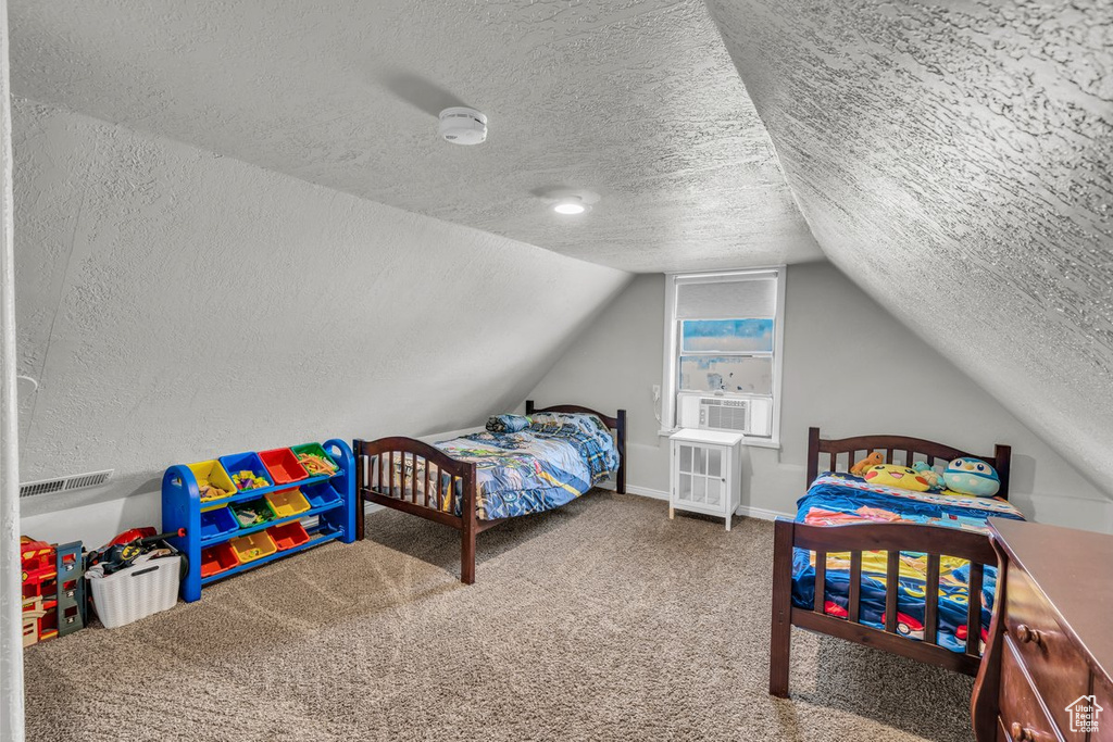 Bedroom with a textured ceiling, lofted ceiling, carpet, cooling unit, and baseboards