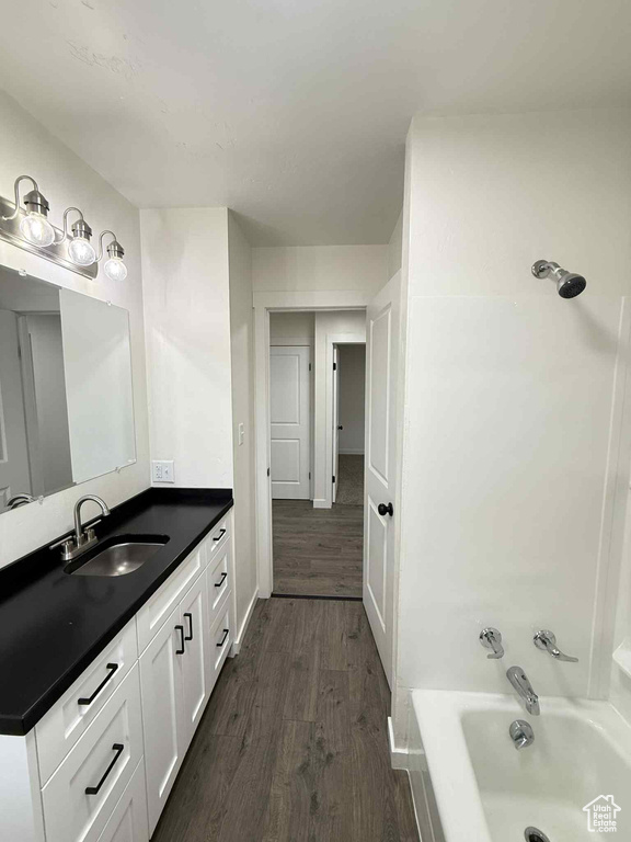 Bathroom with wood finished floors, vanity,  shower combination, and baseboards