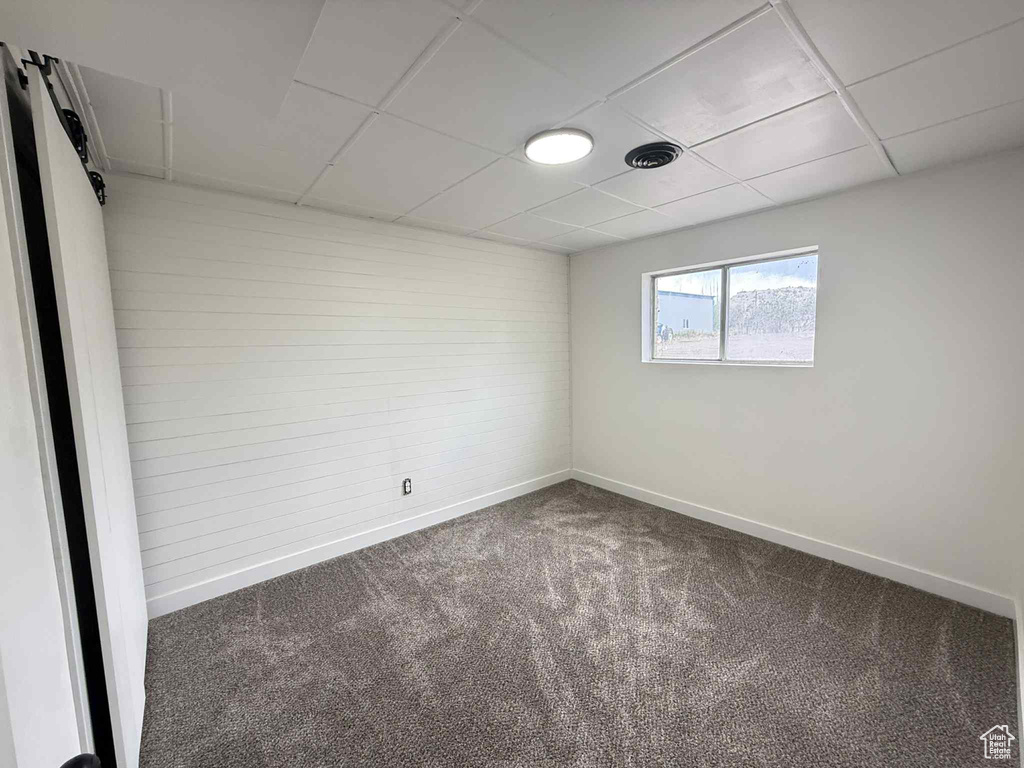 Carpeted spare room featuring a drop ceiling and baseboards