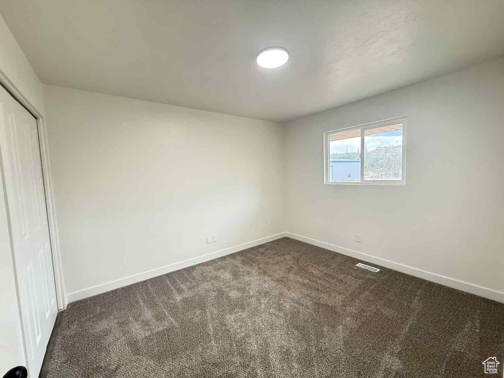 Unfurnished bedroom with baseboards, dark colored carpet, and a closet