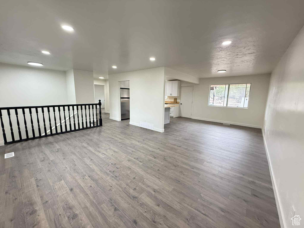 Unfurnished living room with baseboards, wood finished floors, and recessed lighting