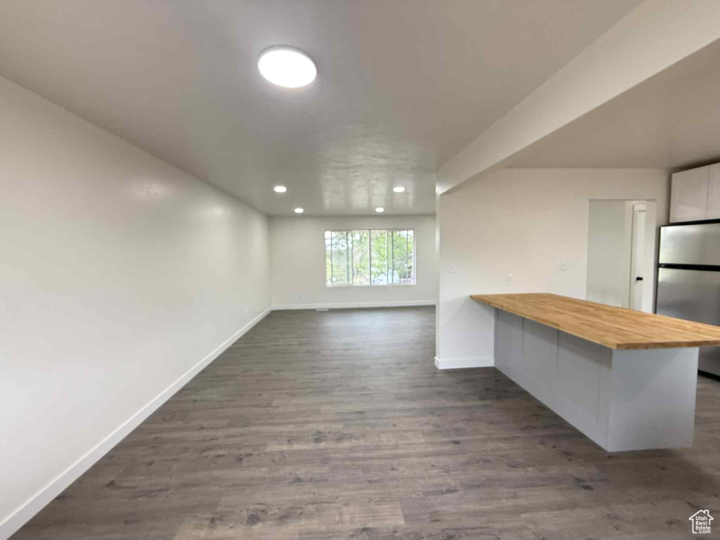 Interior space featuring baseboards, dark wood-type flooring, and recessed lighting
