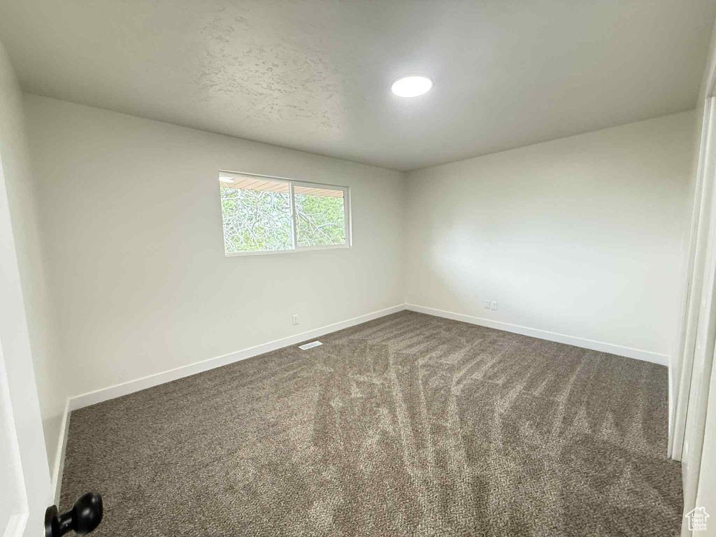 Spare room with baseboards and dark carpet
