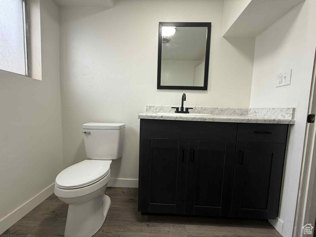 Bathroom featuring vanity, toilet, baseboards, and wood finished floors