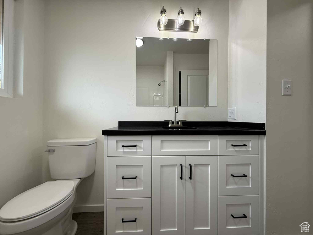 Bathroom with vanity, toilet, baseboards, and a shower