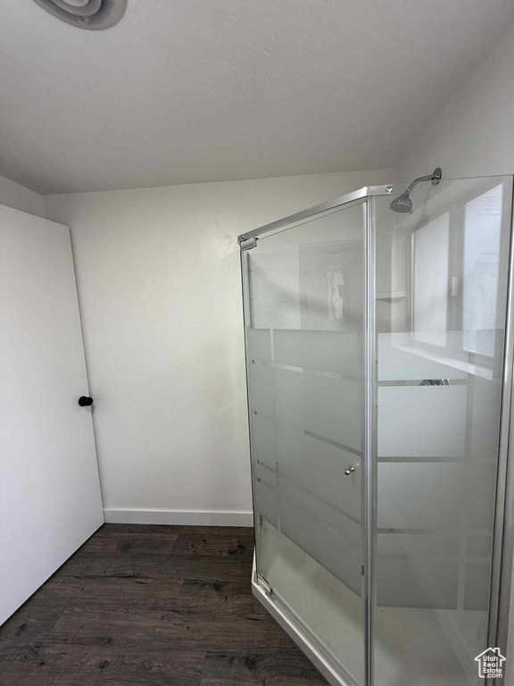 Bathroom featuring a shower stall, wood finished floors, and baseboards