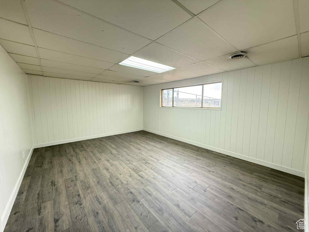 Spare room with wood finished floors, a paneled ceiling, baseboards, and wooden walls