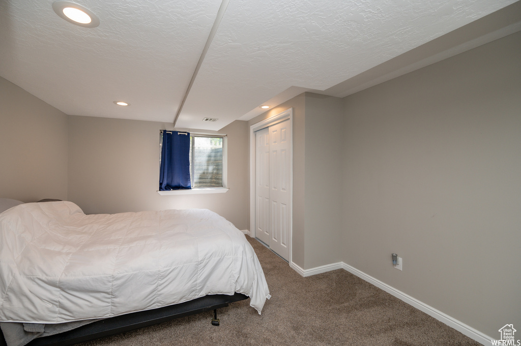 Carpeted bedroom with baseboards, a textured ceiling, a closet, and recessed lighting