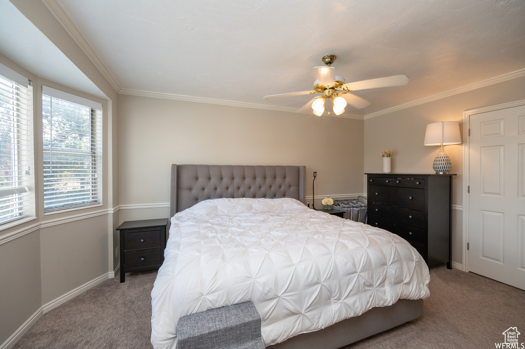 Carpeted bedroom featuring baseboards, ornamental molding, and a ceiling fan