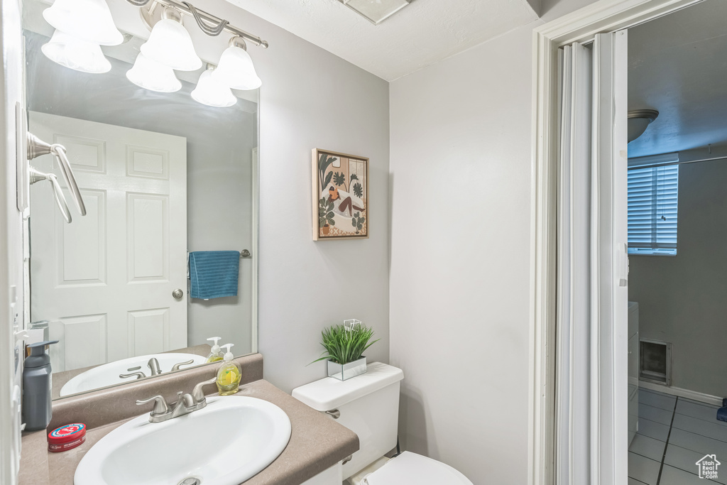 Half bathroom featuring toilet, tile patterned floors, and vanity