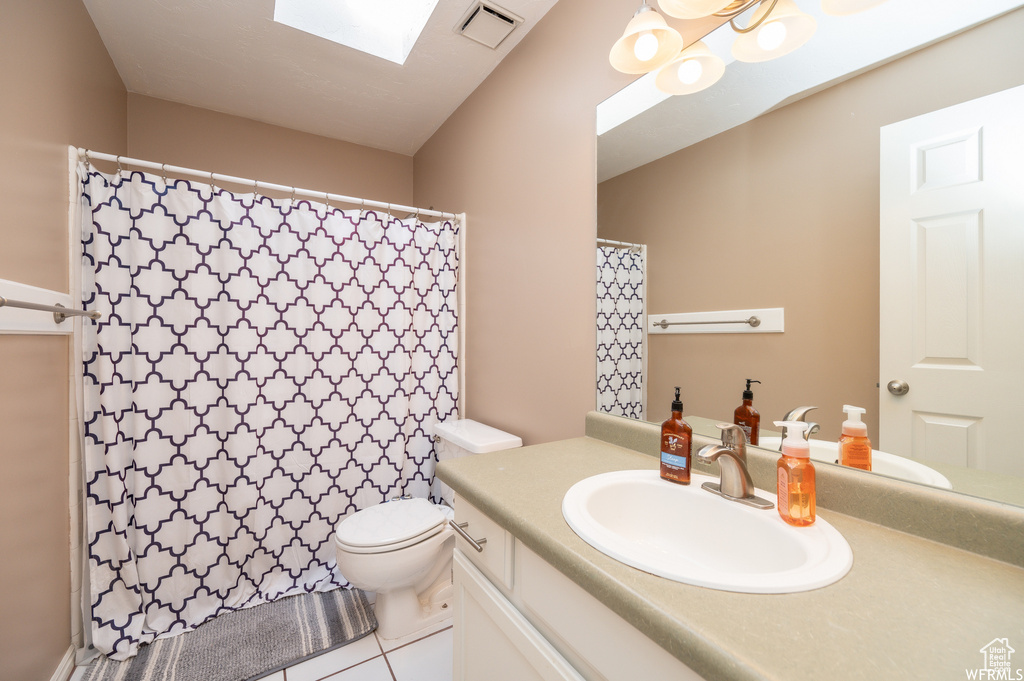 Full bathroom featuring vanity, toilet, tile patterned flooring, a skylight, and a shower with curtain