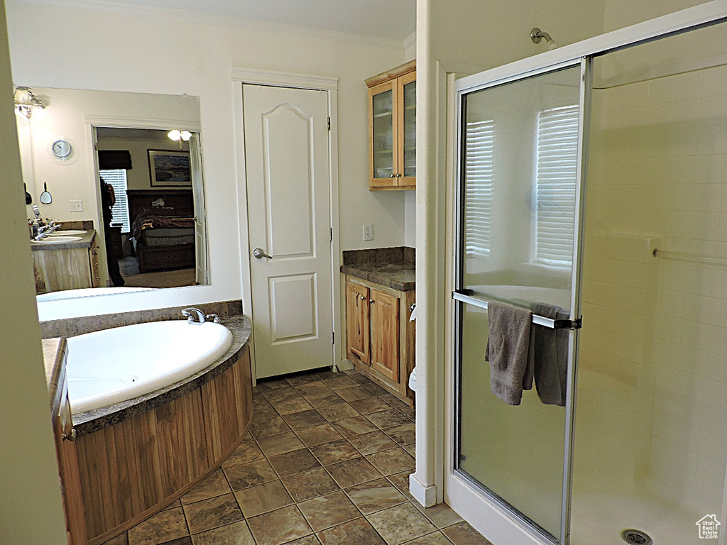 Full bath with a stall shower, vanity, a bath, ornamental molding, and stone finish flooring