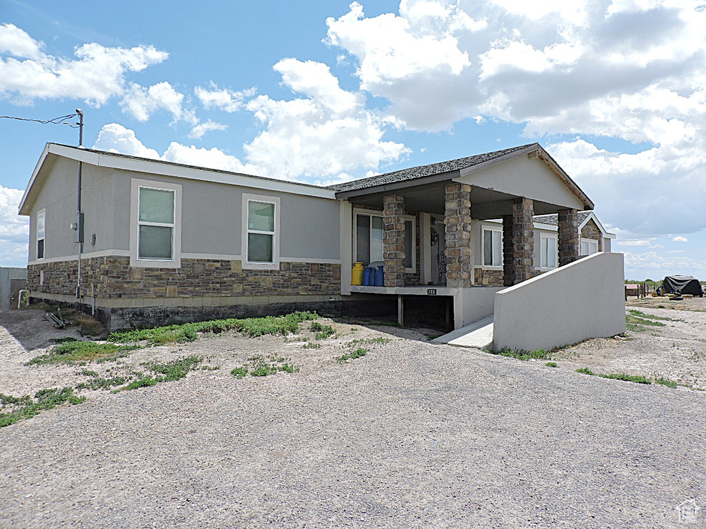 View of front facade featuring stone siding, a porch, and stucco siding