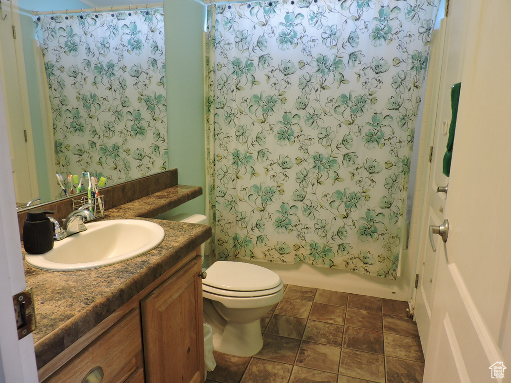 Full bath with vanity, toilet, shower / bath combo, and stone finish flooring