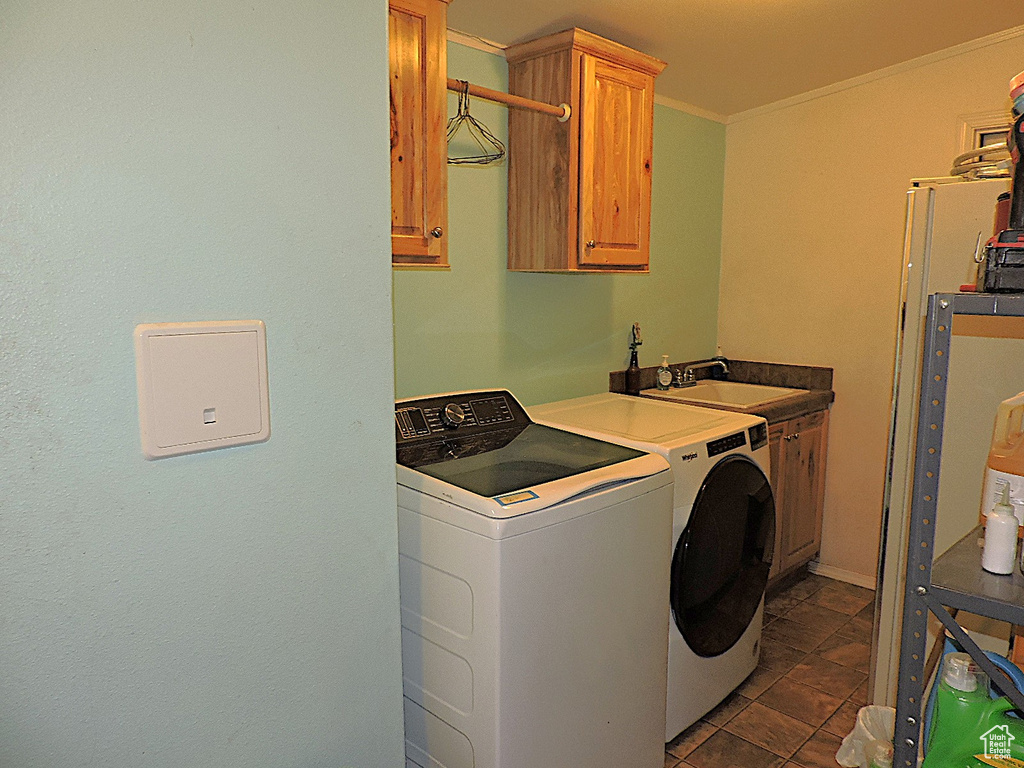 Laundry area with separate washer and dryer, cabinet space, and crown molding