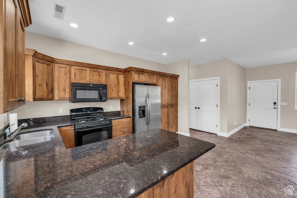 Kitchen with black appliances, a sink, brown cabinetry, recessed lighting, and baseboards