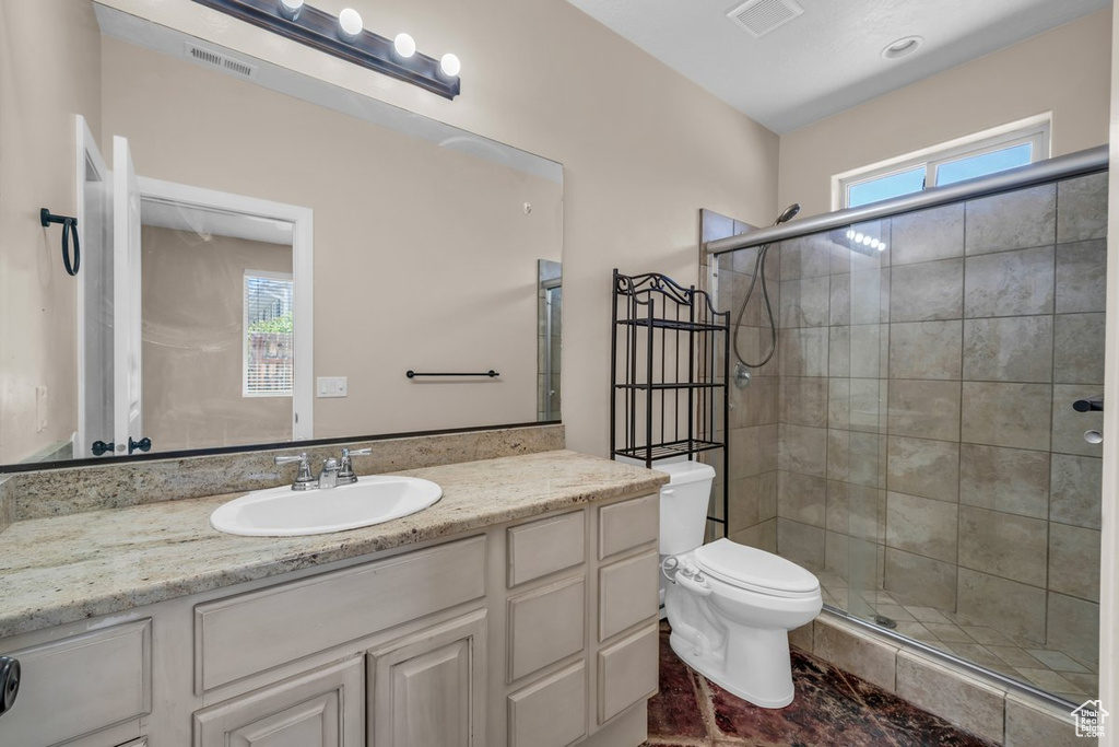 Bathroom featuring vanity, toilet, and a stall shower