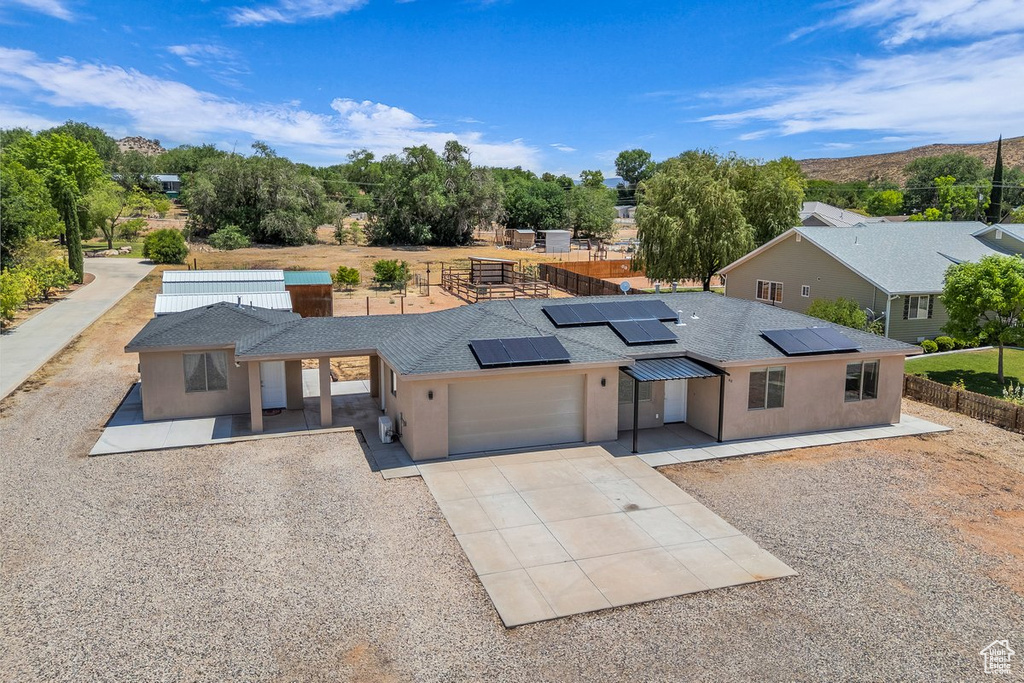 View of front of property featuring an attached garage, concrete driveway, stucco siding, and roof mounted solar panels