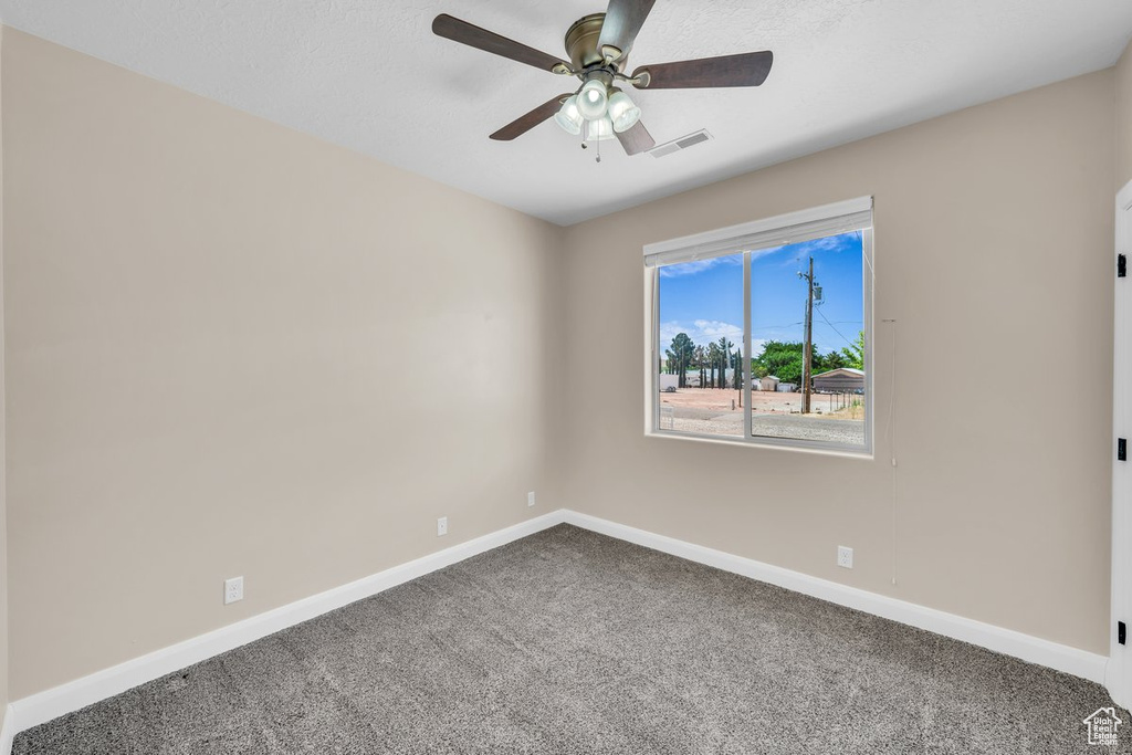 Empty room with carpet floors, baseboards, and a ceiling fan
