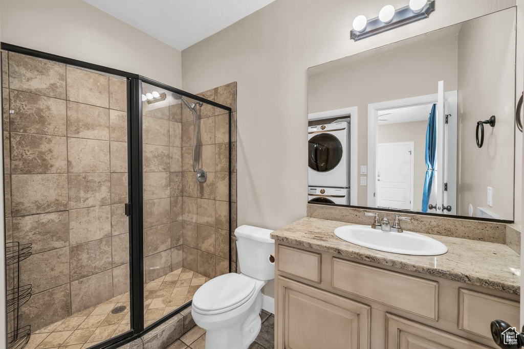 Full bath with stacked washer / dryer, vanity, a stall shower, and toilet