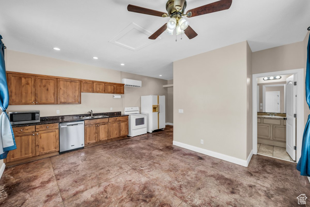 Kitchen featuring stainless steel appliances, dark countertops, an AC wall unit, a ceiling fan, and a sink