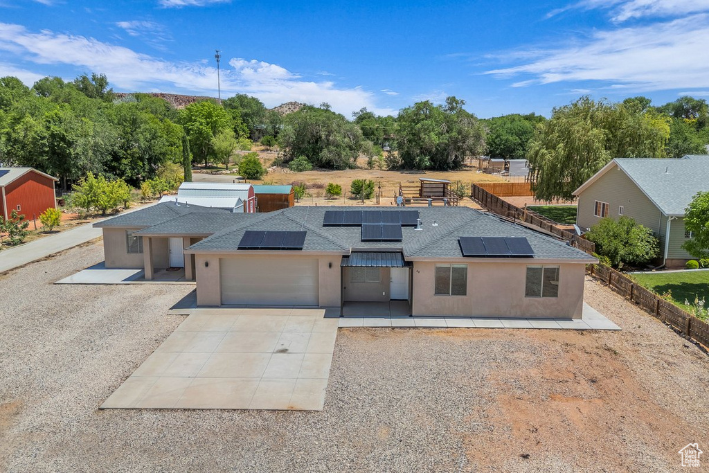 View of front of home with concrete driveway, roof with shingles, stucco siding, solar panels, and a garage