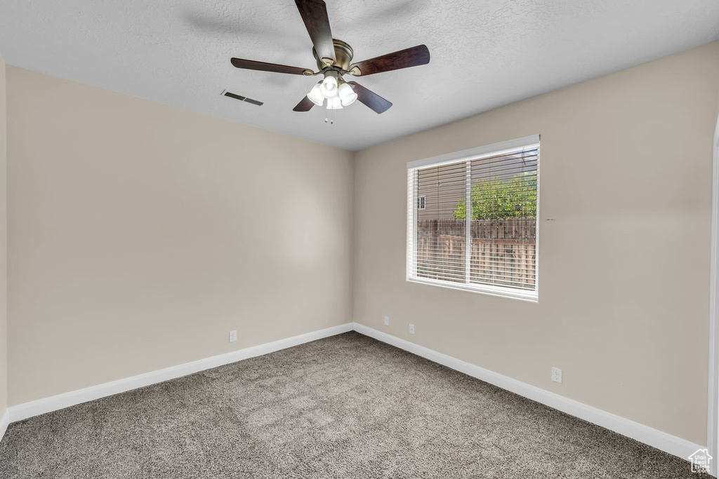 Carpeted spare room with baseboards, ceiling fan, and a textured ceiling