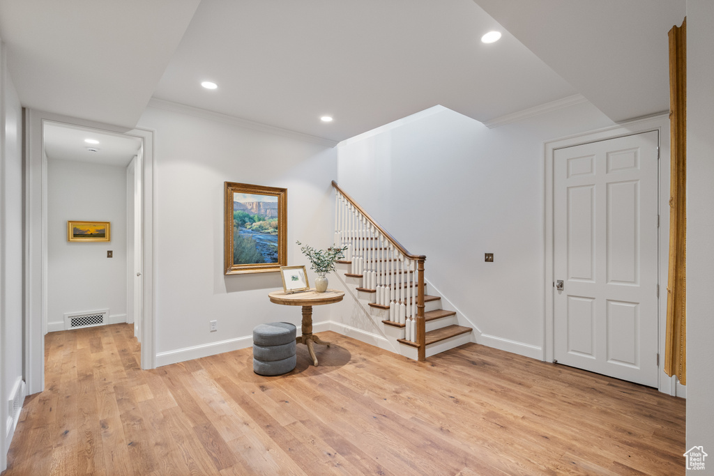Entrance foyer with ornamental molding, recessed lighting, stairs, light wood finished floors, and baseboards