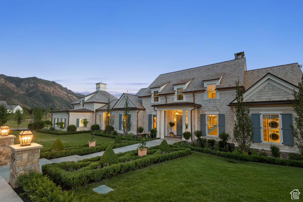 View of front of house featuring a front lawn, a chimney, and a mountain view