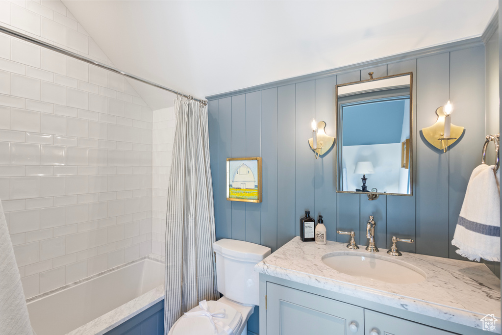 Full bathroom featuring vanity, toilet, shower / bathtub combination with curtain, and lofted ceiling