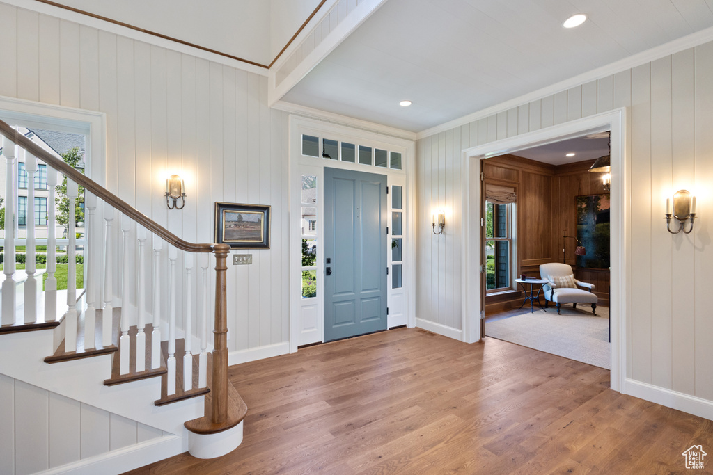 Foyer with crown molding, stairway, wood finished floors, plenty of natural light, and baseboards