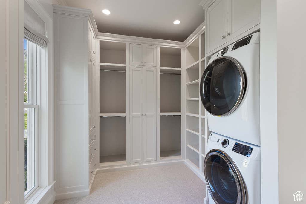 Laundry room with stacked washing machine and dryer, carpet, recessed lighting, and cabinet space