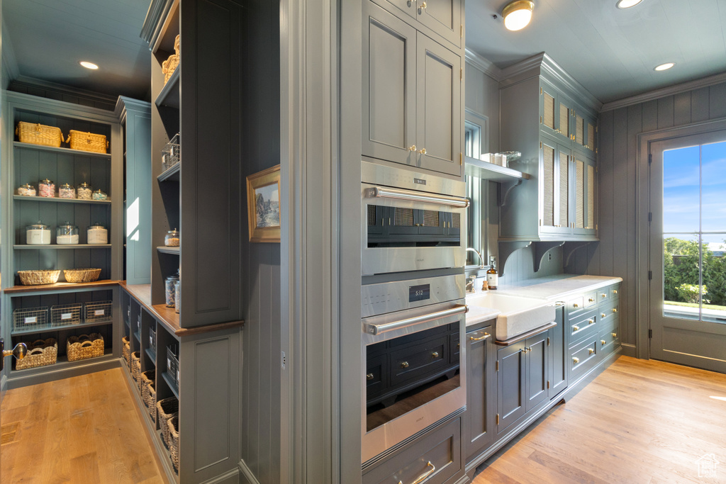 Kitchen with open shelves, crown molding, light wood-style floors, a sink, and light countertops