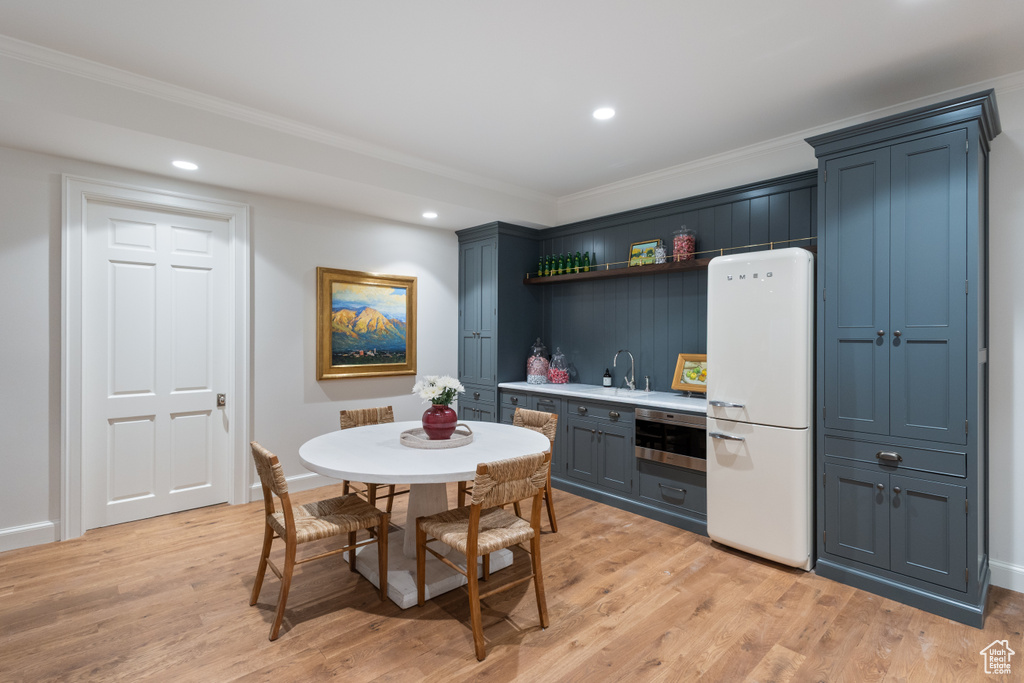 Kitchen featuring freestanding refrigerator, light wood-type flooring, ornamental molding, open shelves, and recessed lighting
