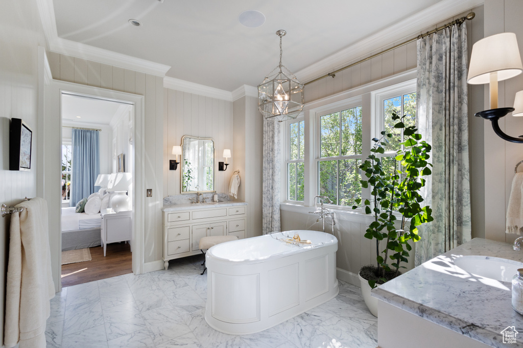 Ensuite bathroom with crown molding, vanity, marble finish flooring, a chandelier, and a freestanding bath