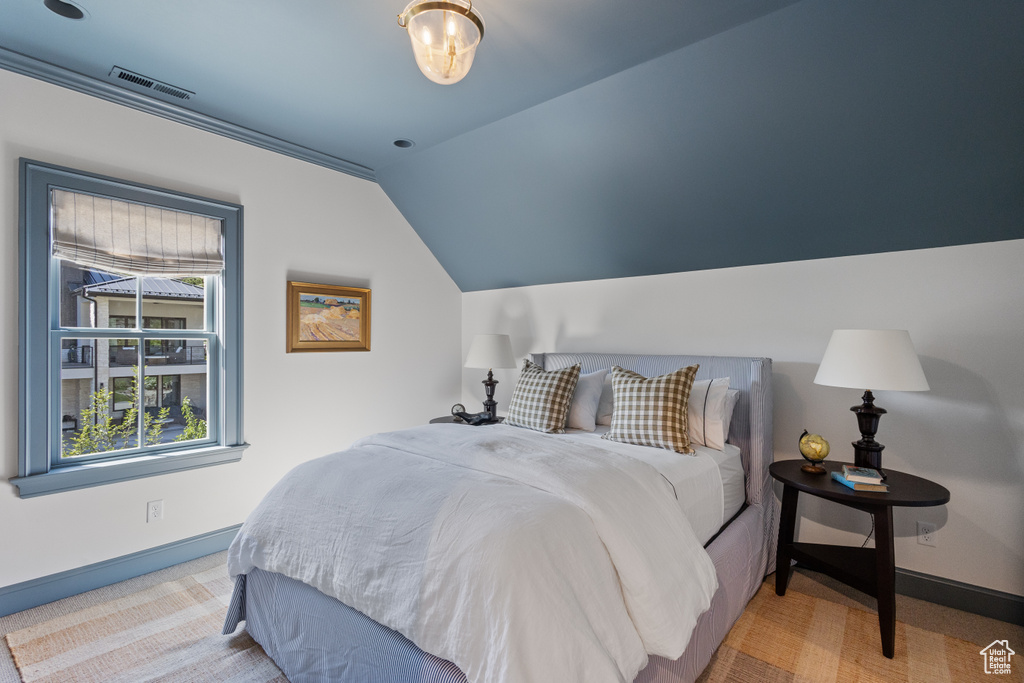 Carpeted bedroom featuring lofted ceiling and baseboards