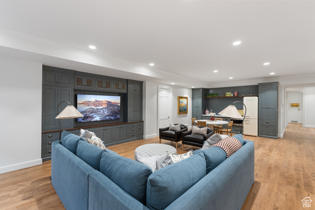 Living area with baseboards, recessed lighting, light wood finished floors, and ornamental molding