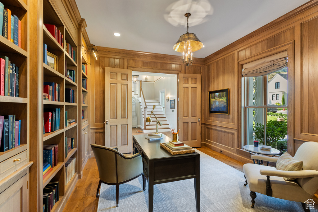 Home office featuring ornamental molding, light wood-style flooring, and wooden walls