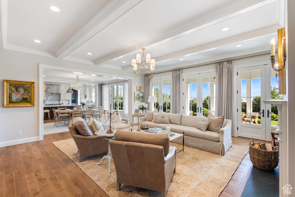 Living room featuring beam ceiling, light wood-style flooring, crown molding, french doors, and baseboards