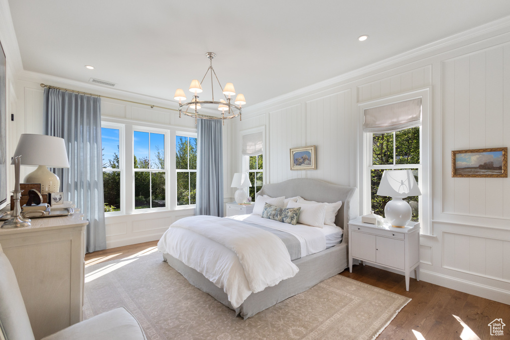 Bedroom with a decorative wall, a chandelier, wood finished floors, ornamental molding, and recessed lighting