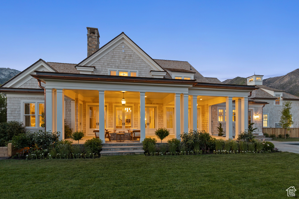 Back of property featuring a porch, a chimney, a yard, and a mountain view
