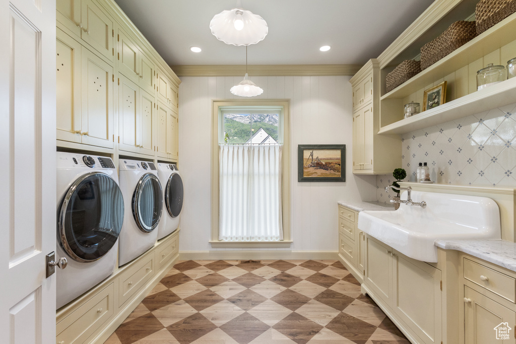 Washroom with washing machine and clothes dryer, cabinet space, baseboards, light floors, and crown molding